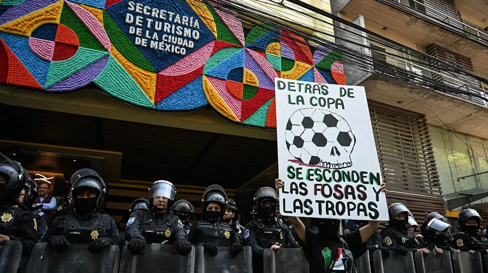 agentes-de-policia-antidisturbios-montan-guardia-mientras-una-manifestante-sostiene-una-pancarta-contra-el-mundial-de-la-fifa-frente-al-edificio-de-la-secretaria-de-turismo-en-ciudad-de-mexico-el-27-de-febrero-de-2